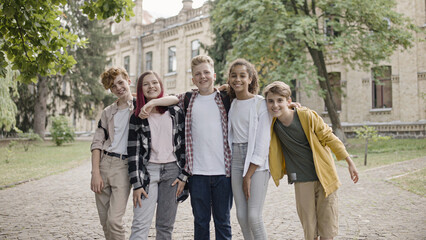 Happy multiethnic school children hugging and smiling on camera, friendship