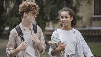 School friends walking home together after classes, having fun and talking