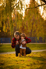 Fototapeta premium Father and son in a park blowing a dandelion flower