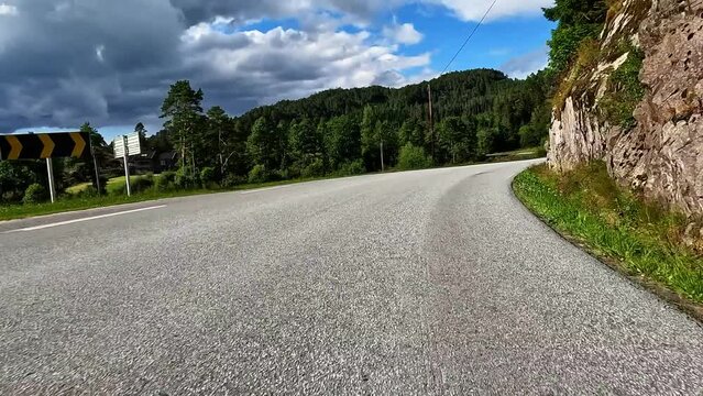 First person view of a nordic road, Norway, lush green sunny contryside