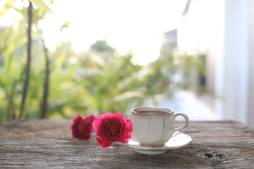 Vintage old eathenware coffee cup and red roses fl0ower on wooden table