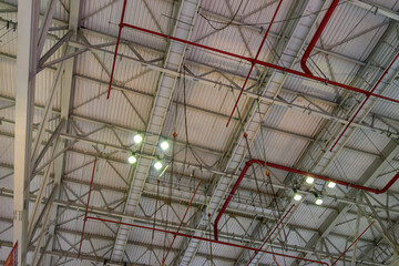 The steel construction roof of a sports hall and the spot lights on this roof. Wide shot of industrial hall empty and clean. Empty factory interior or storehouse
