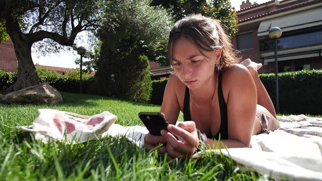 Sexy young woman sunbathing and looking at her smartphone in the grass area of the swimming pool, Sant Cugat del Valles, Catalonia, Spain.
Static camera movement, mid angle, 4K.