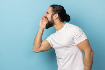 Attention, announcement. Side view of handsome man with beard wearing white T-shirt screaming...