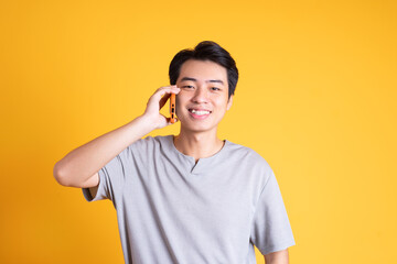 Asian young man posing on a yellow background