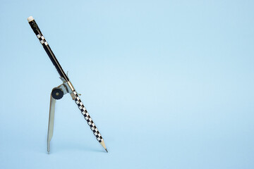 pencil with compass on blue background with copy space