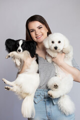 Happy girl holding cute bichon and papillon dogs.