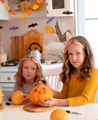 Two cute happy sisters holding Halloween pumpkins. Happy autumn lifestyle kids portrait.