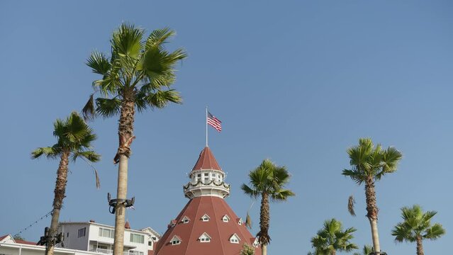 San Diego travel background, American flag is waving in slow motion at hotel resort on Coronado island. Scenic sunny day in tropical nature with palm trees and clear blue sky. Tourism footage on RED 