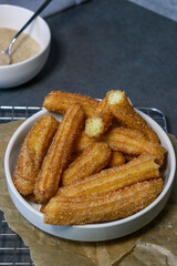 churros with sugar in white bowl on grey table, top view