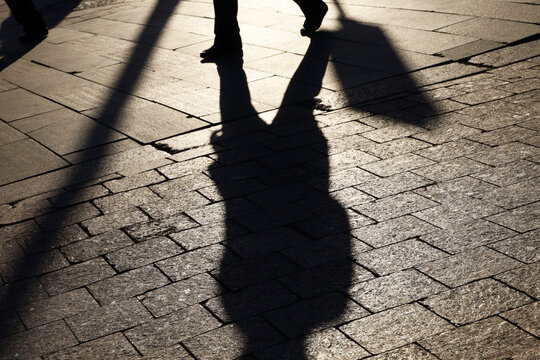 Long Shadow Of Man Walking On City Street, Selective Focus On Sidewalk