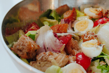 Healthy grilled chicken Caesar salad with tomatoes, cheese, eggs and croutons. North American cuisine.