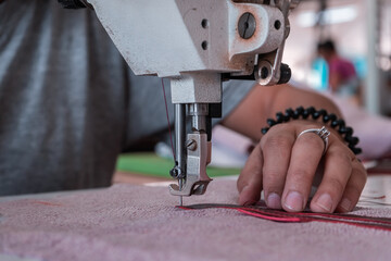 The seamstress sews at the sewing machine, threads the fabric. Women's hands