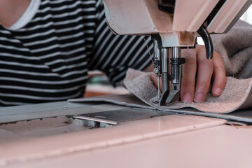 The seamstress sews at the sewing machine, threads the fabric. Women's hands