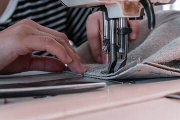 The seamstress sews at the sewing machine, threads the fabric. Women's hands