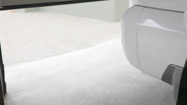 Garage doors with an electric motor automatically close after the car has driven inside. Inside a large garage with sliding entrance gates there is a white car