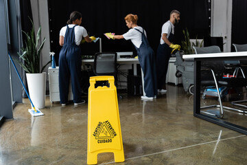 attention sign board near multiethnic professional team cleaning modern office.