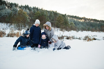 Mother with four children in winter nature. Outdoors in snow.