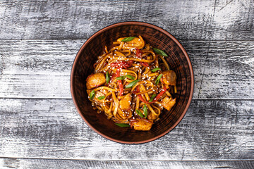 Wok, chicken noodles on a white wooden background