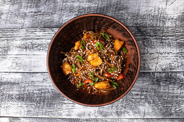 Wok, chicken noodles on a white wooden background