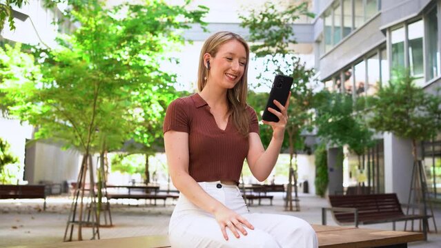 Shot of a student girl doing a video call. She is greeting her friends at the university campus during a break