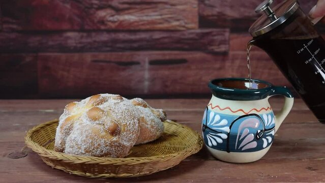 serving french press coffee to a mexican mug alongside traditional day of the dead bread