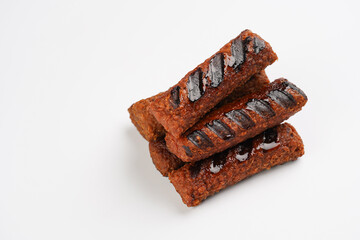 Traditional south european skinless sausages cevapcici made of ground meat and spices, vegan substitute made of soy protein, stacked on white background