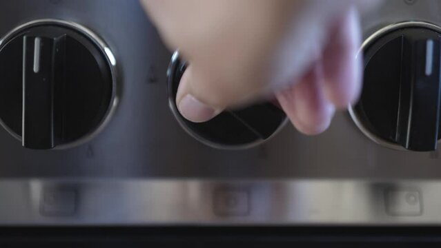 Closeup of a hand turning off the gas stove to save money due to high price of natural gas in Europe.