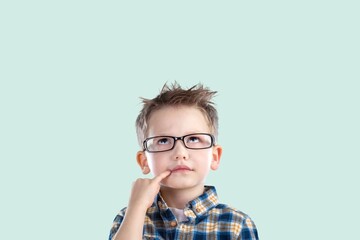 Cute little child in eyeglasses looking at colorful background