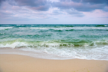 stormy weather in velvet season. seascape with clouds in evening light. waves crashing sandy beach. windy weather
