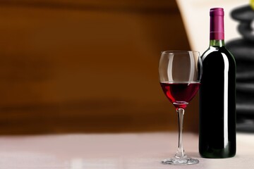 Bottle of tasty wine with a glass on desk
