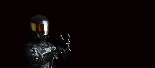 motorcyclist in protective gear and a helmet puts on leather gloves. Biker uniform.