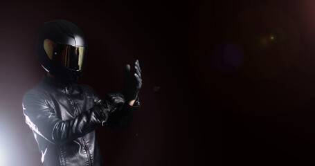 motorcyclist in protective gear and a helmet puts on leather gloves. Biker uniform.