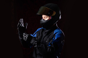motorcyclist in protective gear and a helmet puts on leather gloves. Biker uniform. - obrazy, fototapety, plakaty