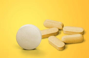 White vitamin pill tablet on color background