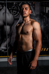 Obraz na płótnie Canvas High quality photography. Athletic latin man posing on a dark background of a gym. Hispanic man posing after training.
