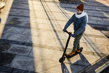 High angle view of young man in warm clothing enjoying his drive on scooter in the city