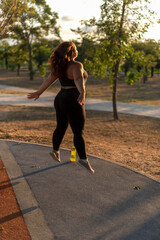 Overweight young woman exercising in the park in the evening, jumping. Weight loss concept