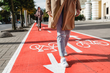 people, city and traffic concept - close up of woman's feet walking along separate bike lane or red...