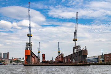 Naklejka premium Hamburg, Germany - July 25, 2022, Alster - Port with shipyards, cranes, logistic facilities and messengers from Hamburg in Germany