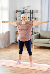 sport, fitness and healthy lifestyle concept - smiling senior woman exercising on mat at home