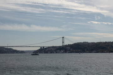 View of a yacht passing on Bosphorus. European side and FSM bridge are in the background. Beautiful travel scene.