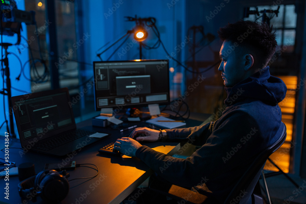 Poster cybercrime, hacking and technology concept - male hacker in dark room writing code or using computer