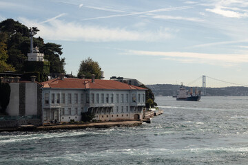 View of historical mansion by Bosphorus in Kandilli area of Asian side of Istanbul. Dry cargo vessel and Bosphorus bridge are in the background. It is a sunny summer day.