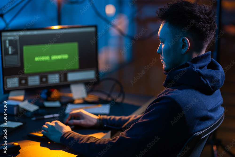 Poster cybercrime, hacking and technology concept - male hacker in dark room writing code or using computer