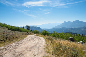 Autumn morning on a bad rural back country dirt road in the mountains on the way to camping with wildfire smoke haze in the distance © TS
