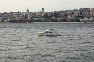 Obraz premium View of a yacht on Bosphorus and Beyoglu district on European side of Istanbul is in the background. It is a sunny summer day. Beautiful scene.