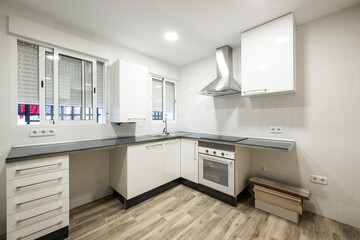 corner kitchen with white cabinets and missing some appliances with wood-look stoneware floors