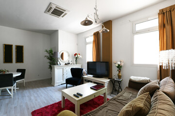 Spacious dining room with white wood and glass window, solid wood sideboards, wicker and glass table, rugs, matching chairs and reddish wood floors