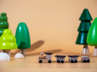 A small wooden locomotive on the background of wooden trees. Travel concept. Eco-friendly wooden toys.